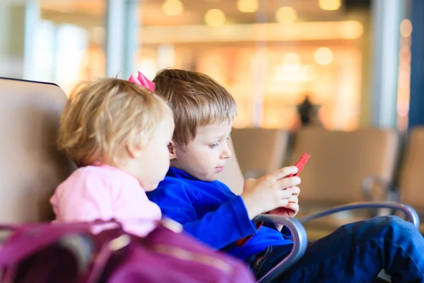 Niño y niña mirando almohadilla táctil mientras viaja en el aeropuerto —  Fotos de Stock