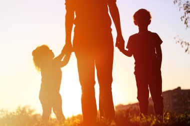 Anne ve iki çocuğu günbatımı üzerinde yürüme