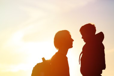 Baba ve sırt çantaları ile küçük oğlu günbatımında seyahat