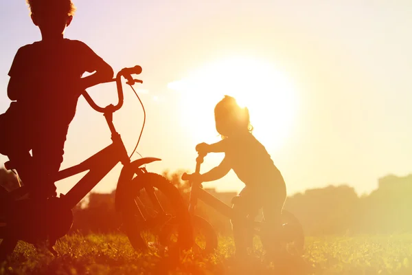 Bambino e ragazza in sella alle biciclette al tramonto — Foto Stock