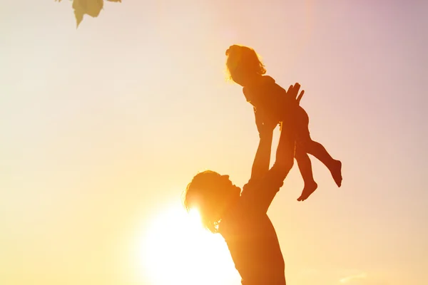 Silhouettes of father and little daughter playing at sunset — Stock Photo, Image