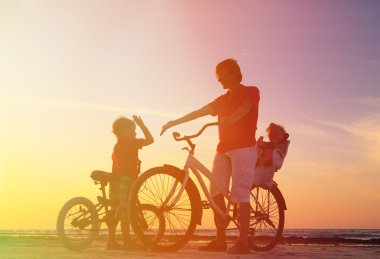 Bisiklet üzerinde iki çocuk ile baba silüeti