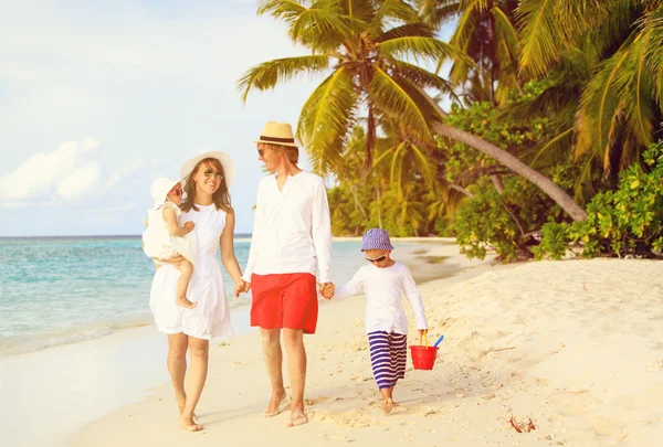 Familia joven con dos niños caminando en la playa — Foto 