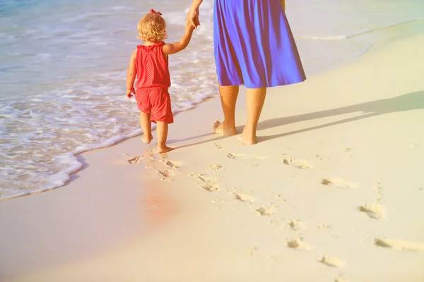 Madre e figlia a piedi sulla spiaggia lasciando l'impronta nella sabbia — Foto Stock