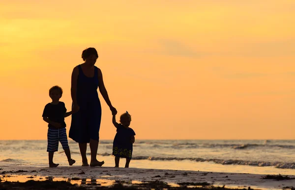 Matka a dvě děti na pláži při západu slunce — Stock fotografie