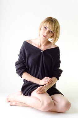 Yana doğru oturan gevşek, büyük siyah süveterli kadın