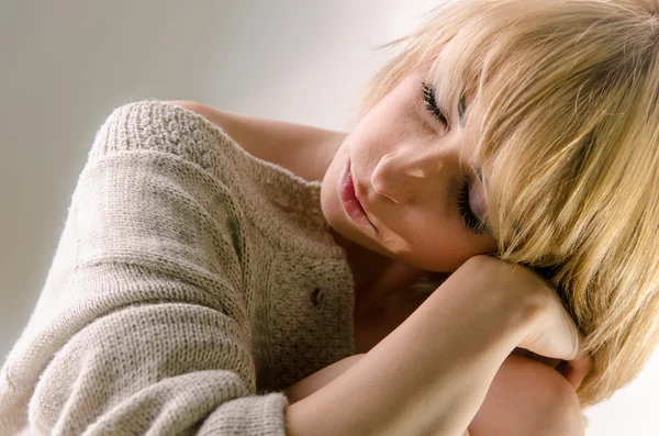 Sleeping blonde young woman dressed in large white cashmere sweater — Stock Photo, Image