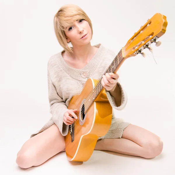 Jovem bela senhora loira sorridente em camisola cinza tocando guitarra acústica — Fotografia de Stock