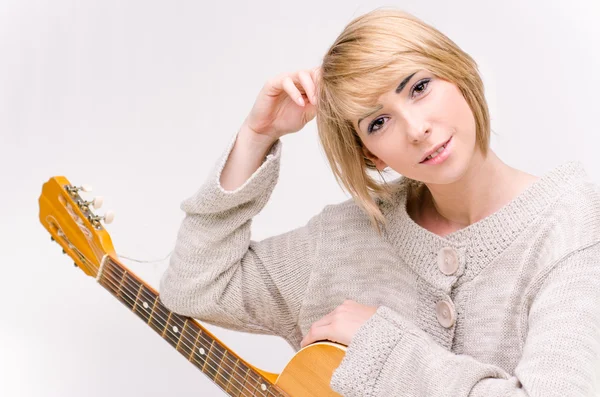 Young beautiful smiling blonde lady in gray sweater playing acoustic guitar — Stock Photo, Image