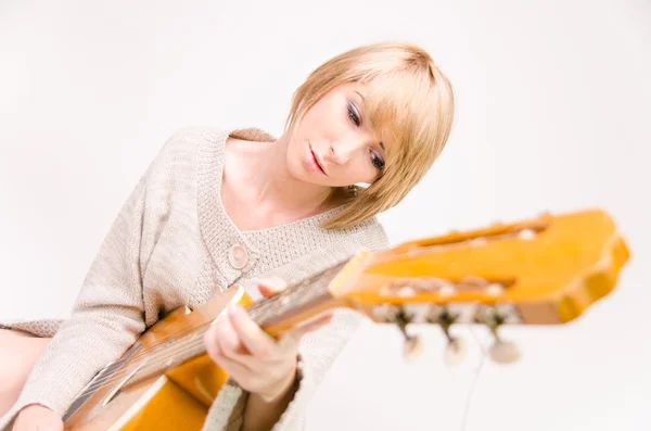 Jovem bela senhora loira sorridente em camisola cinza tocando guitarra acústica — Fotografia de Stock