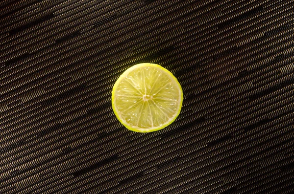 Φέτα λεμόνι ή lime σε μαύρο φόντο με ρίγες — Φωτογραφία Αρχείου