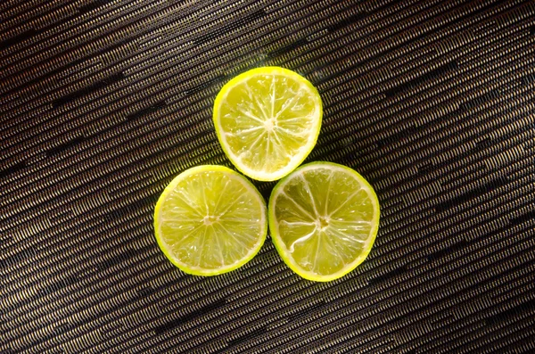 Slice of lemon or lime on black background with stripes — Stock Photo, Image