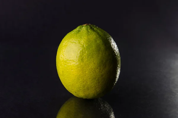 One whole lime on black background, horizontal shot — Stock Photo, Image