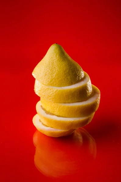 Whole sliced lemon on red background, vertical shot — Stock Photo, Image