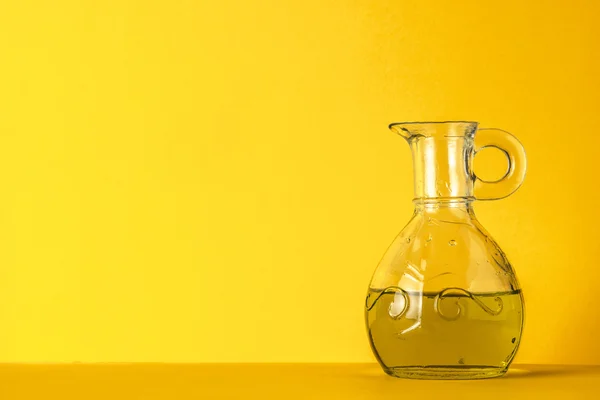 Aceite de oliva en frasco de vidrio sobre fondo amarillo — Foto de Stock