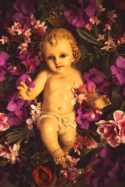 Alte Figur Des Christkindes Umgeben Von Blumen Verschiedener Sorten Retro — Stockfoto