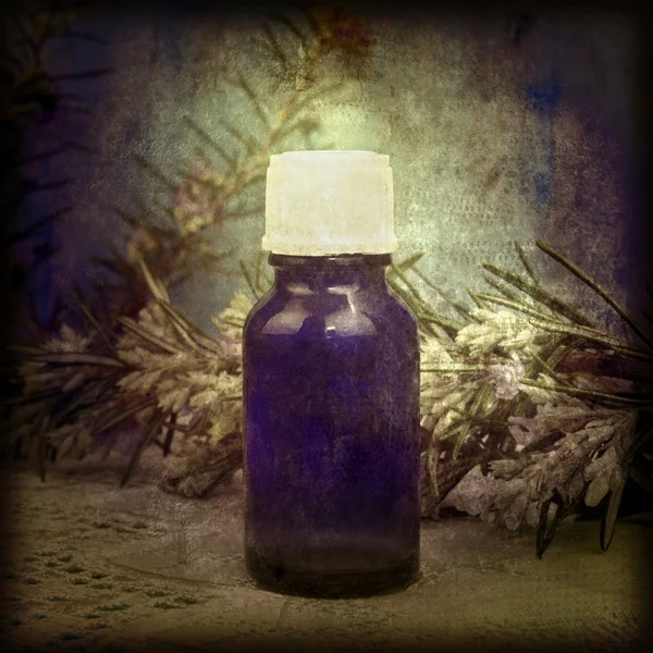 Glass bottle of essential oil and rosemary branch — Stock Photo, Image