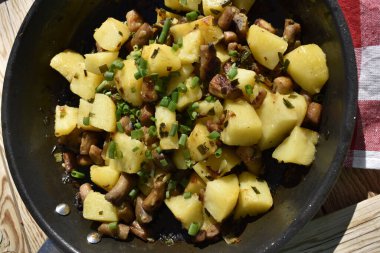 Close-up of fried potatoes with mushrooms and green onions, top view