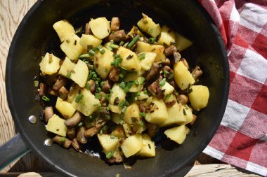 Close-up of fried potatoes with mushrooms and green onions, top view