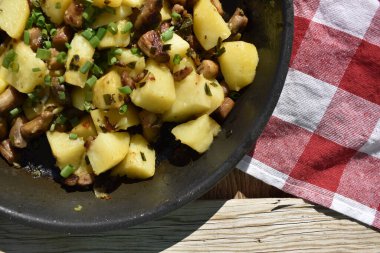 Close-up of fried potatoes with mushrooms and green onions, top view