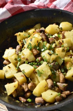 Close-up of fried potatoes with mushrooms and green onions, top view