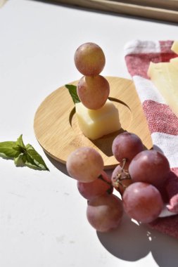 Cheese and Grape Skewer with Basil on Wooden Plate with bunches of grapes