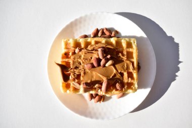 Karamel kremalı Belçika waffle 'ları ve beyaz tabakta fıstıklar.