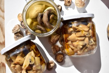 Bir kavanoz mantar turşusu ve iki kavanoz kapalı mantar.