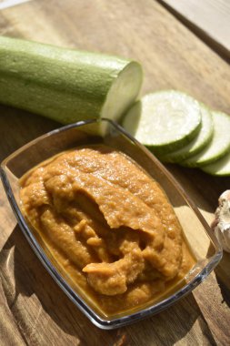 Cam kasede kabak, dilimlenmiş taze kabak ve ahşap zemin üzerinde sarımsak.