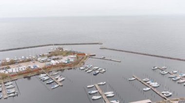 Kopenhag, Danimarka 'nın güneyindeki Brndby Havn limanının hava görüntüleri. İnsansız hava aracı limandan denize doğru eğimli bir açıyla uçuyor. Birçok tekne hala suda, ve bir çoğu da kıyıda. Bugün bulutlu bir sonbahar günü.. 
