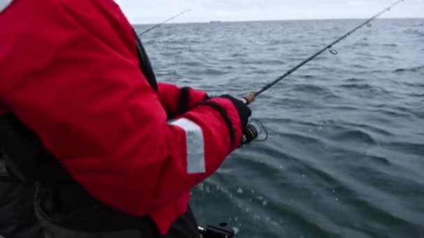 2人の釣り人が開いている海の上の小さなボートの上でタラをジギング 灰色で曇りの冬の日です 波がボートを上下に揺らす — ストック動画