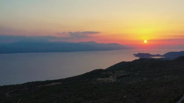 Yunanistan 'daki Gerania dağında güzel bir günbatımının insansız hava aracı görüntüleri. Drone, güneşin battığı yere, denize bakıyor, sonra da Gerania Dağı 'nın yamacını görmek için sağa dönüyor. 4K