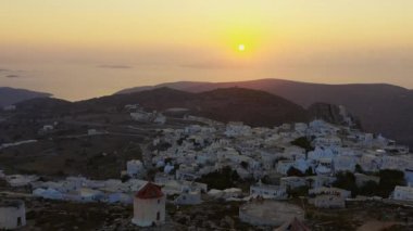 İnsansız hava aracı, Yunanistan 'ın Amorgos kentindeki güzel günbatımını izliyor. İHA havalanıyor ve aşağıdaki küçük köyü görebilirsiniz..