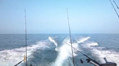 Hızlı balıkçı teknesi denizde su sıçratan dalgalar yaratıyor. Tekne okyanusta hızlı gider, dalgalara çarptığında su püskürtür. Olta kamışı dizildi. Danimarka, Resund 'da güzel bir bahar günü. Gerçek zamanlı 1080p