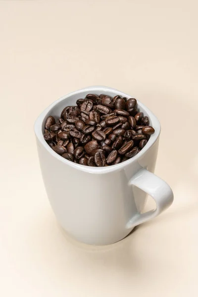 Pražená Kávová Zrna Uvnitř Bílého Šálku Béžovém Pozadí — Stock fotografie