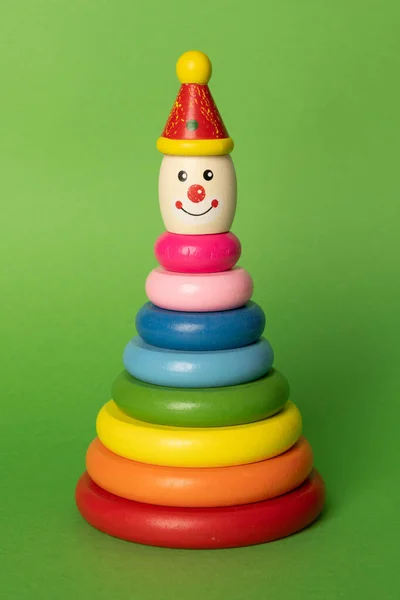 Renkli çocukların renkli arka planda oyuncak istiflemesi. Yürümeye yeni başlayanlar için tahta yüzük istifleme palyaçosu. İstifçi ayağa kalkıyor.