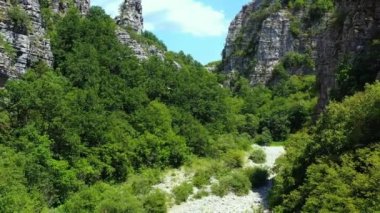 İnsansız hava aracı, Kokkinou, Yunanistan 'daki çok eski taş köprünün üzerinden geriye doğru uçuyor. Güneşli bir yaz günü. Hava aracı 4K stok görüntüsü