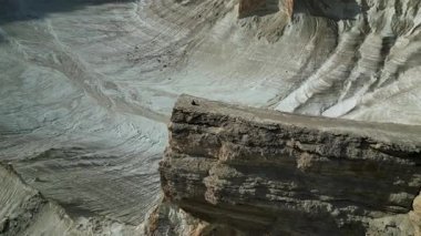 Mangistau 'da. Batı Kazakistan 'daki Ustyurt Platosu' nun uçurumlarının manzarası. Mangistau bölgesinin sonsuz beyaz vadisindeki güzel beyaz kayalıklar. Uçurumun kenarında oturan bir adam. Kuş bakışı görüş.