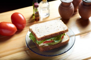 Ispanak, havuç, domates, marul, vejetaryen peyniri ve mayonezi domates, baharat ve baharatlarla çevrili, ahşap masa üzerinde vejetaryen sandviçin en üst görüntüsü. Haşhaş, ayçiçeği, keten tohumu ve yulaf.