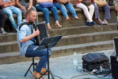 19 Mayıs 2017 - Yakışıklı yetişkin beyaz adam, Piazza della Signoria 'nın arkasında seyirci kitlesiyle sokak konserinde tutkulu bir ifadeyle bandoneon çalıyor..