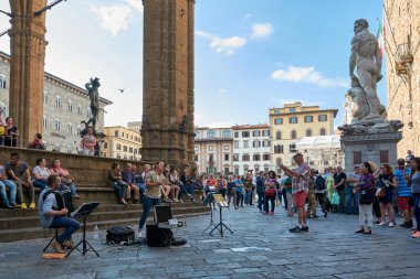 19 Mayıs 2017 - FLORENCE, ITALY: Bir çift sokak müzisyeni tarafından verilen sokak konseri görüntüsü arkasında Piazza della Signoria 'nın gösterisini ve manzarasını izleyen bir kalabalık.