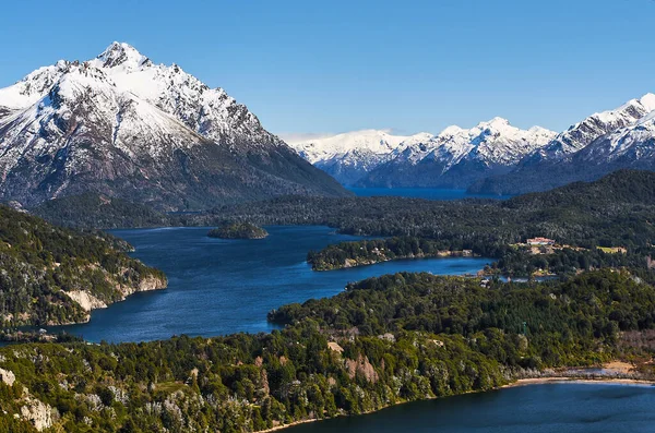 San Carlos de Bariloche, Rio Negro, Patagonya Arjantin 'deki Cerro Campanario (Campanario Hill)' den güzel karlı dağlar ve yeşil ağaçlar manzarası. Llao Llao Oteli sağ tarafta..