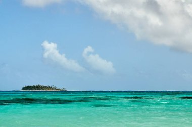 Kolombiya 'daki tropik ada Johnny Cay' in yatay görüntüsü, canlı turkuaz okyanusun ortasında ve güzel mavi gökyüzünün altında, yaz günü bulutlarla..
