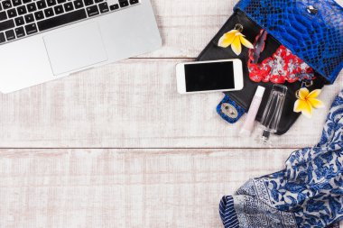 Moda kadın aksesuarları. Lüks el yapımı yılan derisi (python) el çantası, kozmetik, makyaj Aksesuar moda seti, frangipani çiçekler, dizüstü bilgisayar, smartphone, külot. Üstten Görünüm, düz yatıyordu, açık ahşap renkli. Metin için ücretsiz/boş yer. Toplantı.