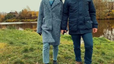 Genç bir çift el ele tutuşuyor. Autumn Park 'ta. Yavaş çekim görüntüleri.