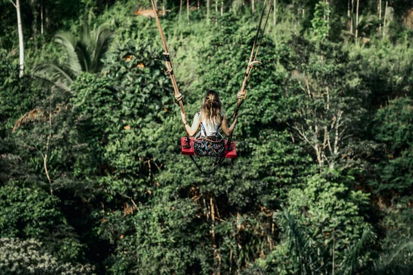 Mujer joven se balancea en la selva de la isla de Bali. Selva tropical de Indonesia. Concepto de viaje. — Foto de Stock