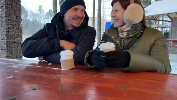 คู่รักหนุ่มสาวดื่มกาแฟด้วยกันกลางแจ้งในช่วงฤดูหนาว คู่รักโรแมนติก การเคลื่อนไหวช้า . — วีดีโอสต็อก