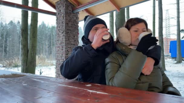 O par jovem bebe o café em conjunto ao ar livre no tempo de inverno. Casal romântico. Movimento lento. — Vídeo de Stock