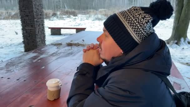 冬の時期にコーヒーを飲んでいる若い男性. — ストック動画