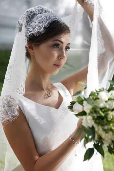 Krásná nevěsta s kyticí v parku — Stock fotografie